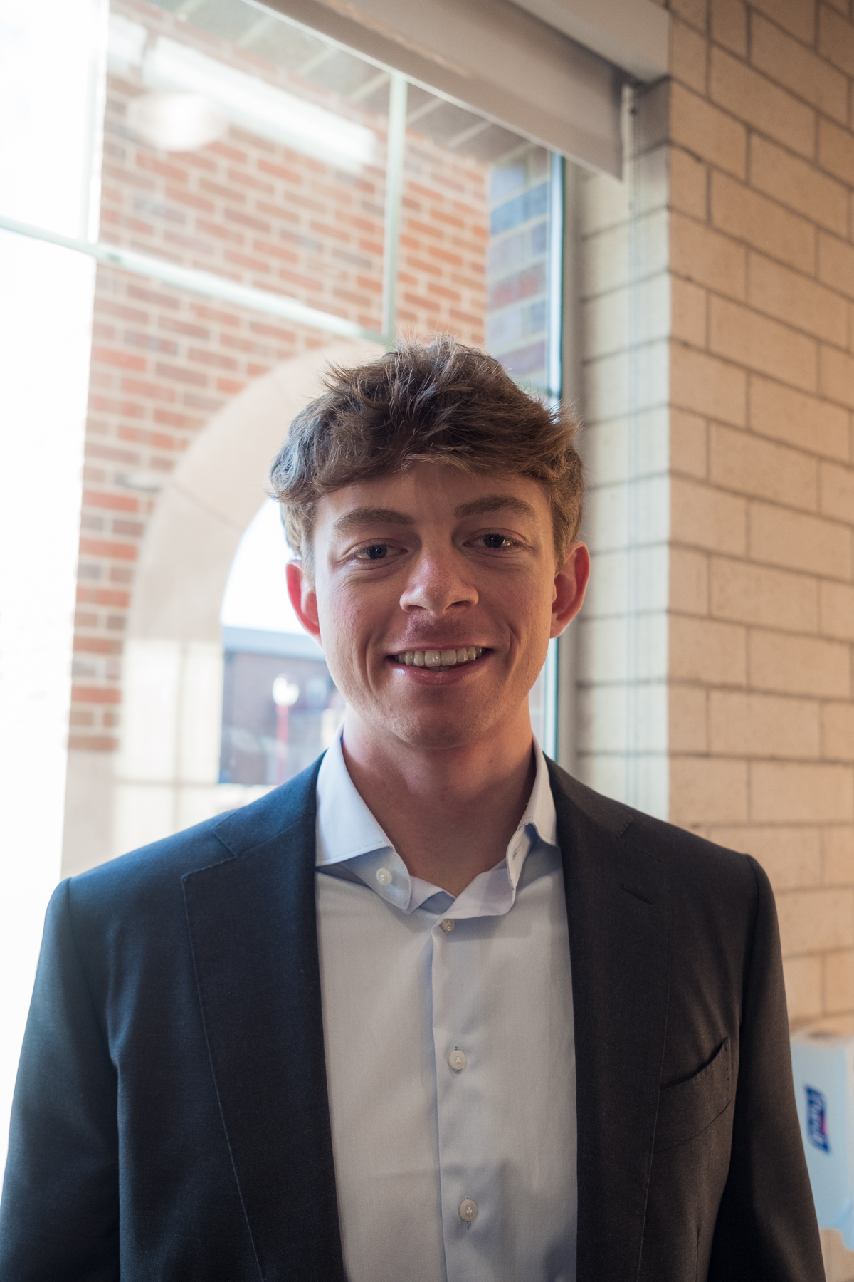 Professional headshot of a man in a dark blazer by a brick archway